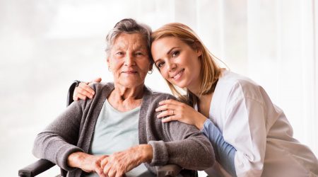 Health visitor and a senior woman during home visit. Portrait of a nurse and an elderly woman in an wheelchair.